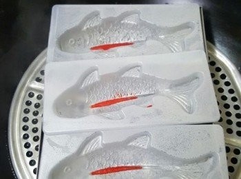 step7: 此時將魚模塗上一層薄薄的油，在蒸鍋子中加水加熱至水滾後，將魚旗部份先加入紅色粉漿小火蒸1分鐘至凝固，再倒入白色粉漿至魚身一半位置