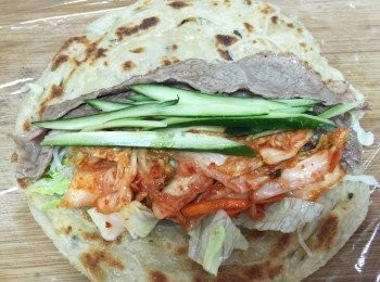 step6: 保鮮膜鋪底，依序放上蔥抓餅、蒟蒻春雨、萵苣生菜、小黃瓜、牛肉片、韓式泡菜後捲起，即可享用。