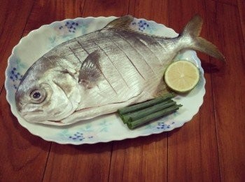 step1: 檸檬切片、青蔥切段、【魚現殺冷凍真空包裝是不讓魚殘留毒素以確品質新鮮，安全衛生看的見！以產地直送的方式，省下中間商轉手與量販店上架費， 辛苦的澎湖漁民們以平實的價格，提供最新鮮<span class="group_1">食材</span>】，黃金錩泡冷水解凍，並將黃金鯧清洗乾淨，用廚房專用餐巾紙擦拭乾，在黃金鯧魚兩面淺劃7-8刀、並抹上少許的鹽，備用；