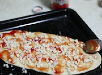 step7: 在餳好的薄餅上，用叉子叉若干小孔，之後抹上一層番茄醬和芝士碎。