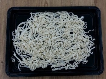 step4: 將麵條放在一個大托盤或烤盤上平鋪,淋上少許的沙拉油(蔬菜油或其他食用油皆可),用筷子將麵條均勻裹上油,並平鋪在盤上快速降溫至冷卻。亦可用電風扇吹涼(麵條會變Q彈),完成後即為"油麵"。