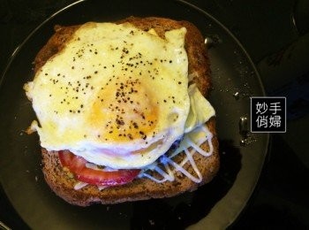 step4: 取出烤完的全麥吐司之後,此時的全麥吐司應該是烤的金黃,而起司呈現半融化狀態,以及冒著熱氣的漢堡肉,這時候就先擠上美乃滋,在超市買的美乃滋在角落剪一個小口之後,就可以輕鬆擠出條狀又細緻的美乃滋,像畫棋盤格子似的擠出棋盤狀後,放上切好備用的番茄片,通常三片成一個小三角形佈滿吐司上即可,放上煎好的荷包蛋,最後再灑上點胡椒粉就完成啦~