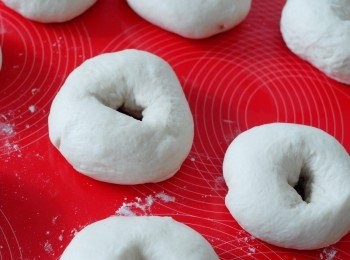 step4: 用手按壓麵糰，用手按壓排出空氣，然後將麵糰分成8份，搓圓，壓扁，在中間弄一個洞，放在灑有麵粉的檯上，用毛巾蓋上，靜置十分鐘