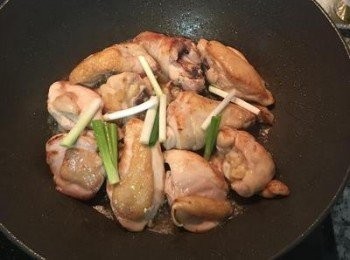 step3: 雞腿皮朝下煎到上色後翻面再煎，煎到差不多時放入蔥白,鹽、香菇精或雞粉拌炒。