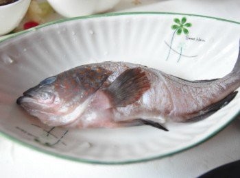 step1: 將新鮮的野生黑毛洗淨，手抓著尾巴用湯匙去鱗片後沖洗，再於兩面用刀子劃3刀