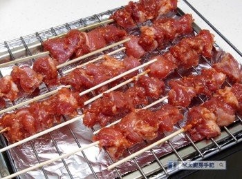 step3: 把醃好的豬肉切成丁，用竹籤串好，放在烤架上。