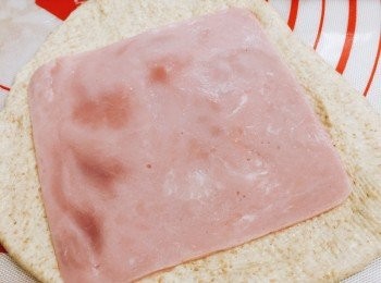 step4: 發酵好的麵團做揉麵排氣，分成8份
每份小麵團先桿平，放上火腿片，再卷好