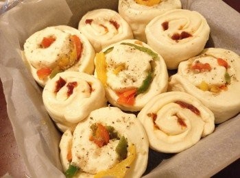 step3: 取出麵糰回溫，排氣，把麵糰分成2份，滾圓。分別用麵棍把麵糰擀成長方型，一份塗抹上蒜蓉醬後鋪上三色椒，另一份鋪上撕碎的蕃茄乾及芝士。各自捲成長條及收口，把收口壓在底，各切成6份，排放於烤模上置室溫發酵至2倍大(約1 小時)。