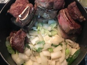 step5: 將煎上色的牛小排延鍋邊堆起來，騰出空間放入大蔥與洋蔥炒香；