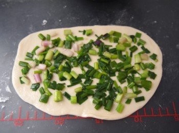 step5: 墊上灑少許麵粉，將醒好的麵糰分成4等份；每份用麵棍擀成長薄片，均勻地抹上少許幼鹽和塗上油及麻油，再鋪上1/4份量的蔥
