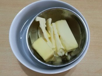step3: 用大碗盛熱水，用小碗盛牛油，將小碗放在大碗內，隔水加熱，待牛油變液體，倒進混合物中，攪拌均勻。