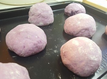 step7: 將小麵糰再次排氣，紫薯餡放入小麵糰中包好，搓圓，排入烤盆中。
