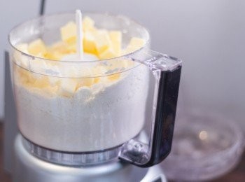 step3: <span class="group_1">撻皮</span>於冰箱取出牛油粒，加入粉類材料內，用食物處理器打一下放一下的方法打至牛油及粉類材料混合成幼粒狀，如麵包糠般的狀態