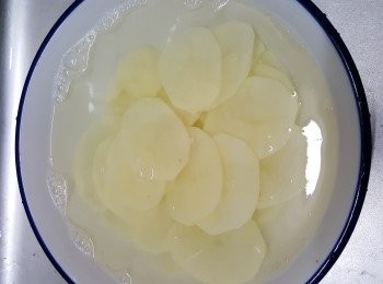step2: 先將焗薯去皮，刨成薄片，浸水一會，盛起，備用。