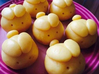 step5: 雪好的麵團分16份，每份先留下一小部分做耳朵和尾巴，其餘的用手壓成邊薄中心較厚的圓形，再包入奶黃餡。放上尾巴和耳朵，用平頭牙籤點上眼睛。做好月餅後，先放入冰箱冷藏約30分鐘再放焗爐焗比較不易變形。