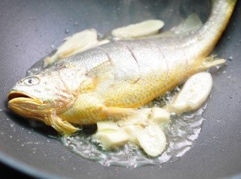 step2: 先將薑片、蒜片爆香，再放入黃魚香煎至兩面微微金黃