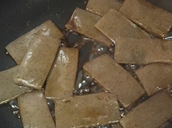 step3: 蒟蒻墨玉板先切三等份後，再將中間切開不切斷，形成口袋的造型，起熱鍋將墨玉板乾煎，待表面水分乾燥後淋上鰹魚醬油，待收乾後即可起鍋放涼備用。