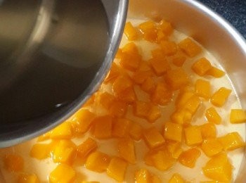 step14: 蛋糕模拎出，將120克芒果粒平鋪在已經凝固的乳酪芝士面上，將一半荔枝味啫喱水倒入，剛剛蓋過芒果肉，入雪櫃雪30分鐘，拎出模具，倒入剩餘的啫喱水，再次移入雪櫃，冷藏4小时以上，或者雪過夜會更佳