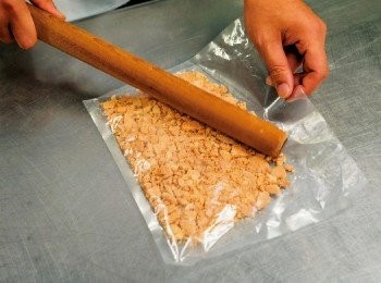 step1: 將全麥餅乾放入封口袋，用擀麵棍敲成碎片，倒入缽盆。加入杏仁、融化的奶油、細砂糖 10 g 攪拌均勻。