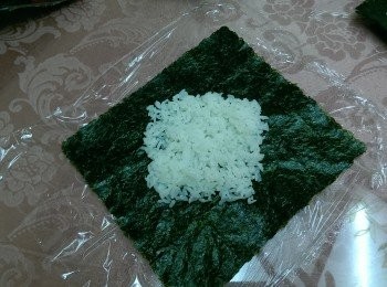 step4: 桌上先鋪上保鮮膜,取一片海苔片,擺成菱形,將白飯鋪在中間(正方形)