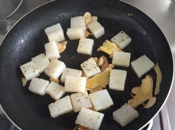 step4: 取炒鍋，加入1大匙麻油，放入薑片、蒜片和以中小火爆香，再加入蒟蒻白玉板及辣椒片一起翻炒。