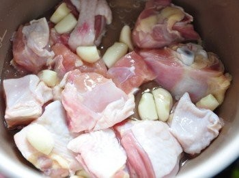 step3: 先將雞肉塊與蒜頭放入飛利浦智慧萬用鍋內鍋中，灑上適量的鹽，淋上少許的蔥油(青蔥+橄欖油低溫煸熱)及米酒