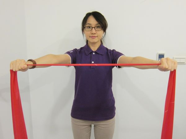 動作2：維持原姿勢，施力將彈力帶往兩邊平行拉開，大於肩寬。